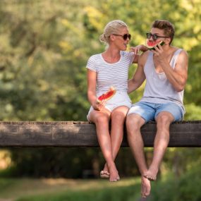 Couple mangeant une pastèque sur une branche en été